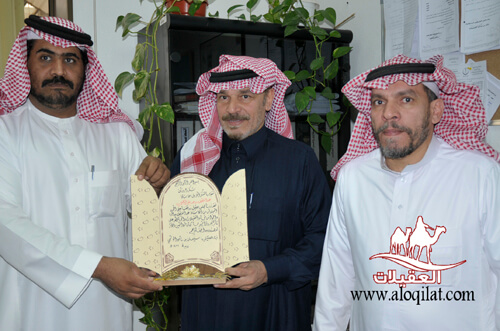 ثلاثة رجال يرتدون الزي التقليدي السعودي، يحمل أحدهم شهادة أو لوحة بشكر في وسط الصورة.